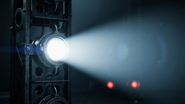 Stage lighting technician adjusting spotlight in theater with focused beam and dark background