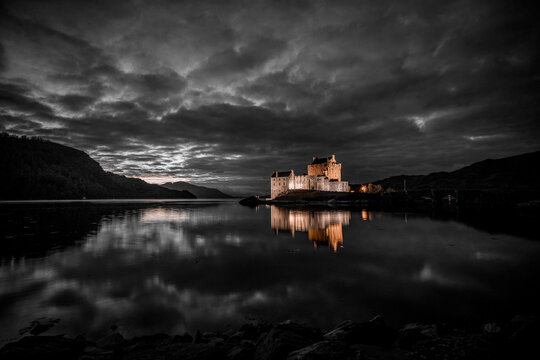 Eilean Donan Castle illuminated at night, sitting on the waters of Loch Duich in the Scottish Highlands