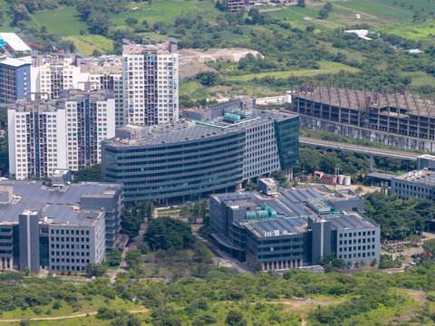 Aerial view of Hinjewadi Phase III tech park featuring modern glass-facade office buildings, solar panels on rooftops, and surrounding lush greenery in Pune, Maharashtra, India.