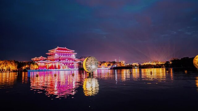 Illuminated Traditional Chinese Pavilion and Moon Sculpture Reflecting on Lake at Night in Xi an, China