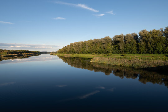 A scenic shot of the Danube River, flowing peacefully among the trees. The sky is reflected in the water.