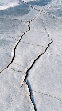 Cracked ice surface, winter landscape with fissures, cold atmosphere
