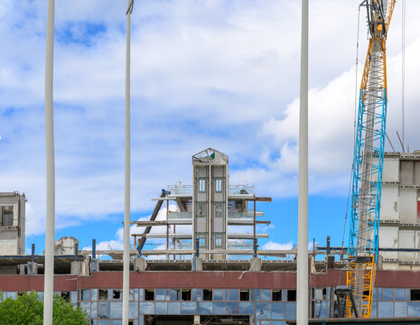 Large industrial building undergoing demolition with crane and containers.