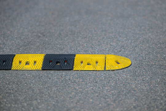 Black and yellow modular speed bump on asphalt road.