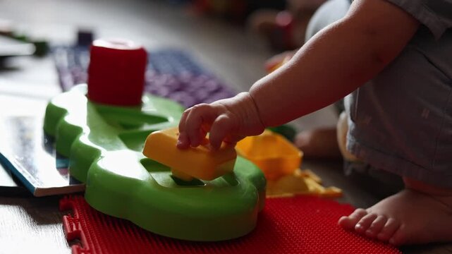 A toddler plays with a colorful plastic shape sorting toy on a textured floor at home