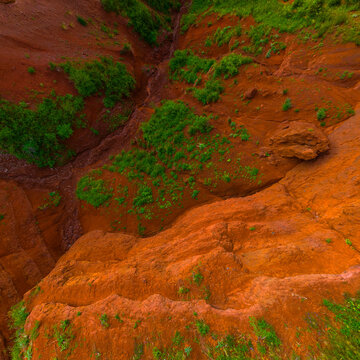 Aerial View of Eroded Landscape with Red Soil and Green Vegetation