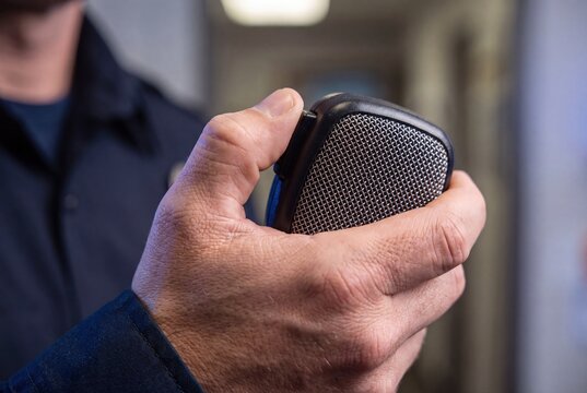 Police officer holding shoulder microphone radio device close up portrait