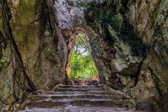 A view up steps towards a rock archway on an upper level of the Marble Mountains in Da Nang, Vietnam on a bright sunny day