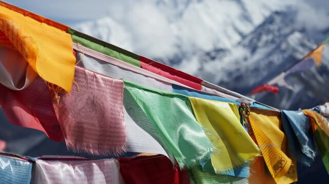 Colorful Tibetan Prayer Flags Fluttering Against Snowy Himalayan Mountain Peaks in Himalayas