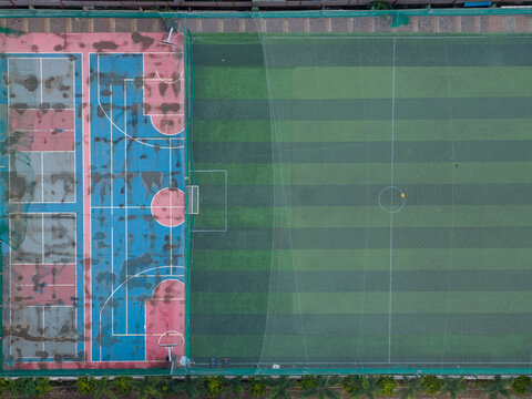 Aerial view of Punawale sports complex featuring a vibrant blue and red basketball court adjacent to a green artificial turf football field in Pimpri-Chinchwad, Maharashtra, India.