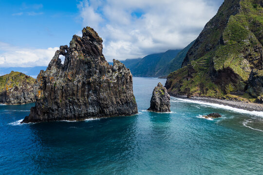 Volcanic cliffs and ocean at Ribeira da Janela, Madeira island. Atlantic coast with natural rock formations and green mountains