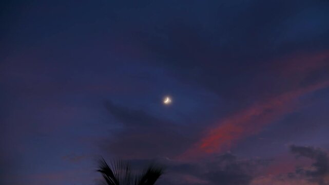 Timelapse of the bright Venus planet and crescent Moon appearing near each other in the vibrant evening sky at twilight and during a planetary conjunction.