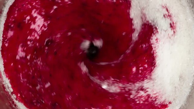 Grinded Berries in Blender. The berry mass mixed with sugar slowly comes into motion under the action of blender knives
