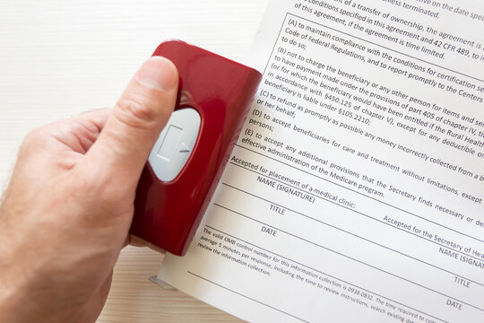 A person uses a hole punch to make holes in a document in order to secure a paper form in an office binder.