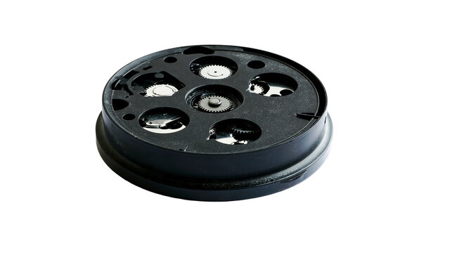 Isolated circular black mechanical part with internal visible gears on a pristine surface.