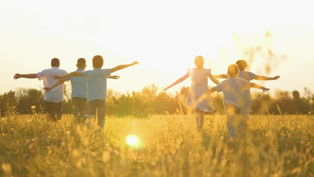 Child kid superhero, childhood dream flying, mother father run nature sunset, family running park summer, family time under a warm sky, backlit family silhouettes in a wildflower meadow, pure
