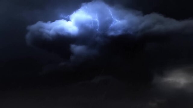 Dark storm clouds fill a shadowy nighttime sky above a barely visible landscape