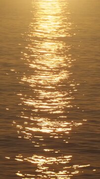 Golden sunset reflection shimmering on sea water, with gentle waves and glowing ripples forming abstract background for meditation. Vertical video. 