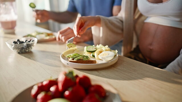 Pregnant couple eating breakfast kitchen. Closeup avocado toast healthy plate.