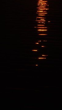 Thin streaks of light glints from the sun on the dark water.