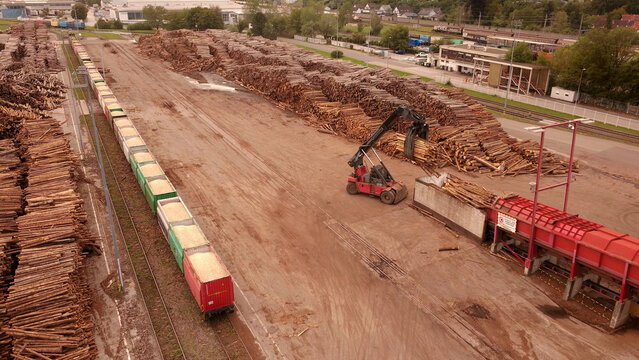 Aerial view of a paper mill log yard with a crane loading timber onto a freight train in Graz, Styria, Austria.