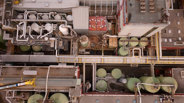 Aerial view of a paper mill featuring industrial tanks, complex piping systems, and machinery in the early morning light Graz, Styria, Austria.