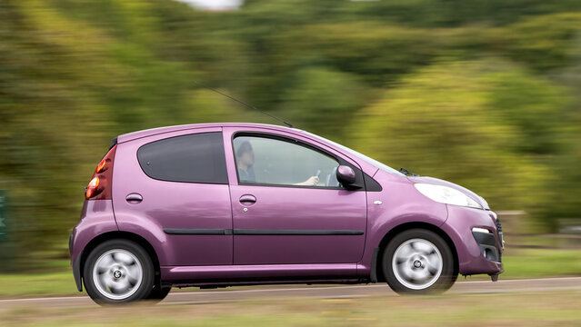 Milton Keynes; UK - Sept. 13th 2026:  2012 purple peugeot 107 hatchback car driving on a British road