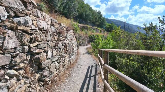 Narrow dirt path beside dry stone terrace with sea beyond. Hiking in Cinque Terre