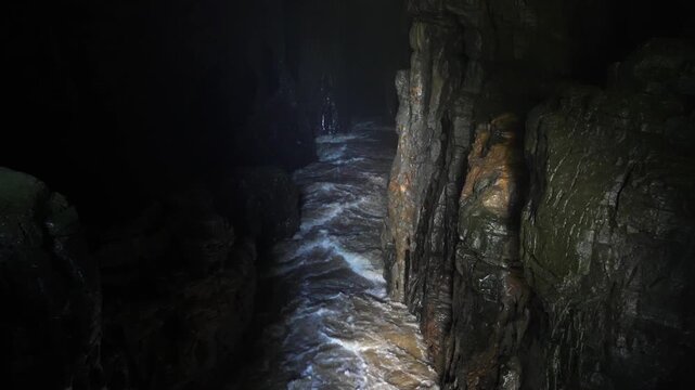 Fast Flowing Water Inside a Dark Narrow Rocky Cave Passage