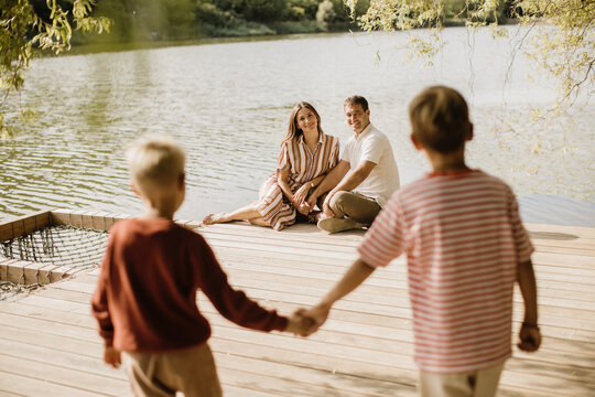 Family bonding moments by the serene lakeside on a sunny afternoon