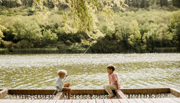 Two children enjoy a peaceful fishing day by a shimmering lake