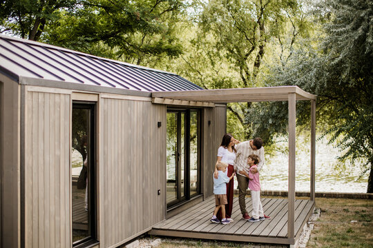 Family enjoying quality time outside a modern wooden cabin in nature