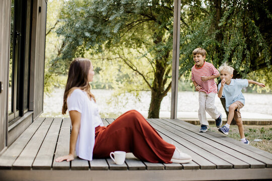 Joyful children playing by the water while their mother relaxes nearby