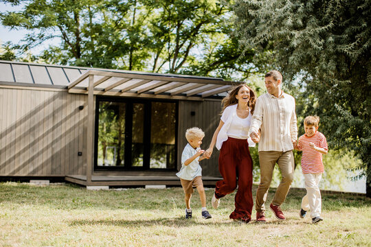 Joyful family walk in nature near a modern wooden cabin