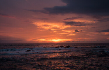 Obraz premium Dramatic red sunset sky over ocean waves in Tamarindo Costa Rica
