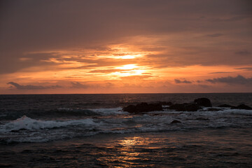 Obraz premium Dramatic red sunset sky over ocean waves in Tamarindo Costa Rica