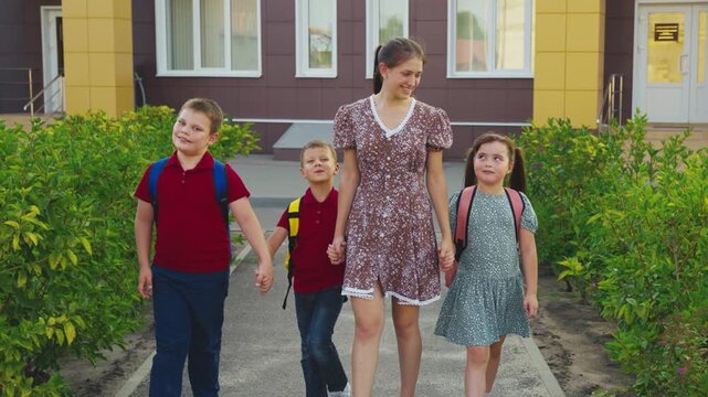 Group of students outside, Holding hands for safety, Safe walk to school, Teacher or older student guiding, Green surroundings, New academic year, Friendship and bonding, School bags packed, Organized