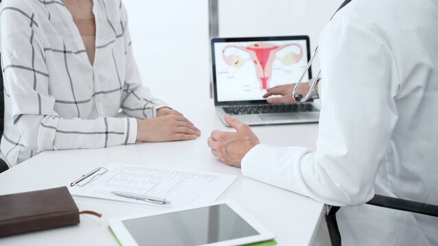 Doctor pointing to a uterus diagram on a laptop. Providing a detailed explanation of female reproductive health to a patient during a medical appointment