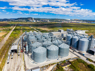 Large storage silos and a railway line near an industrial area on a sunny day with few clouds in the sky © DSMT