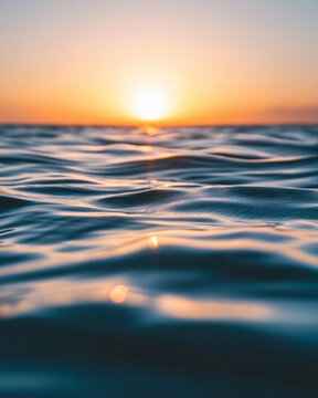Sun setting over calm ocean water with gentle waves