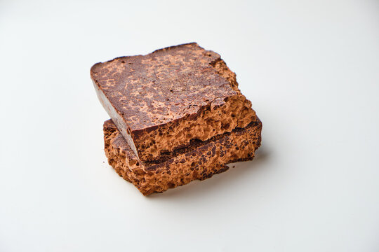 Stacked chocolate brownies with rich frosting on white background