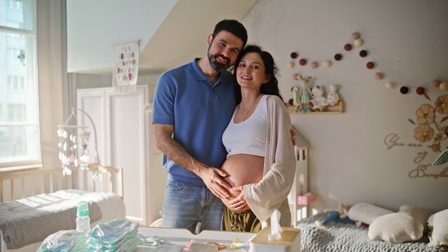 Expecting parents touching belly baby room. Pregnant wife husband bonding home.