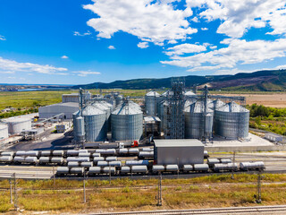 Grain storage facility with silos and railroad tracks in a rural area on a sunny day © DSMT