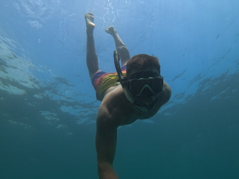 Man freediving underwater in mask and snorkel in clear blue sea water during summer vacation trip in Mediterranean Sea