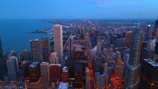 Luminous streets of downtown Chicago stand out in the cityscape at dusk time. Gorgeous city scenery along Lake Michigan from drone.