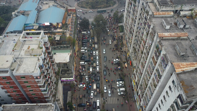 Aerial view of heavy urban traffic and congestion on a busy street with cars and rickshaws between tall residential buildings in Dhaka, Dhaka Division, Bangladesh.