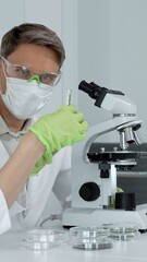 Scientists in laboratory coats. Safety glasses. And masks carefully examining samples under a...