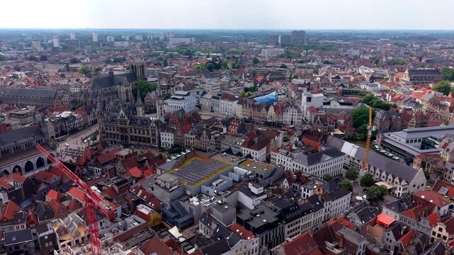 Wide horizontal aerial drone video of Ghent historic city center, Saint Nicholas Church, Old Post Office, rooftops, and cityscape in East Flanders, Belgium on bright afternoon
