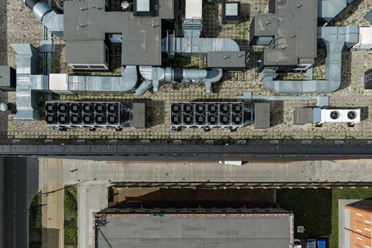 Aerial view of modern self-sufficient office building featuring a rooftop with extensive HVAC systems, ventilation ducts, and green roof elements in Poland.
