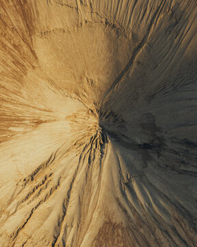 Aerial view of sand piles showing intricate textures, erosion patterns, and golden light casting shadows across the landscape in Poland.